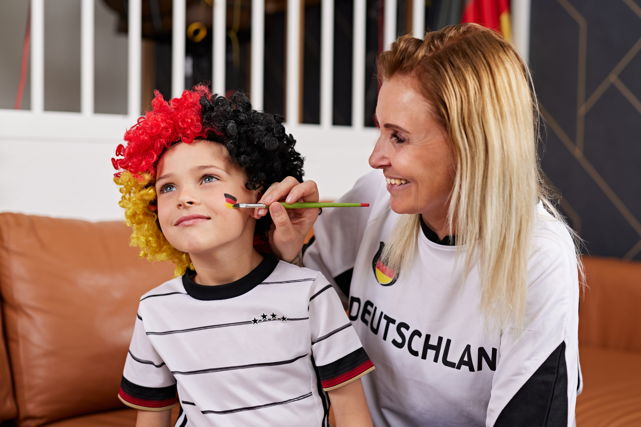 Mama malt Kind Deutschlandflagge ins Gesicht